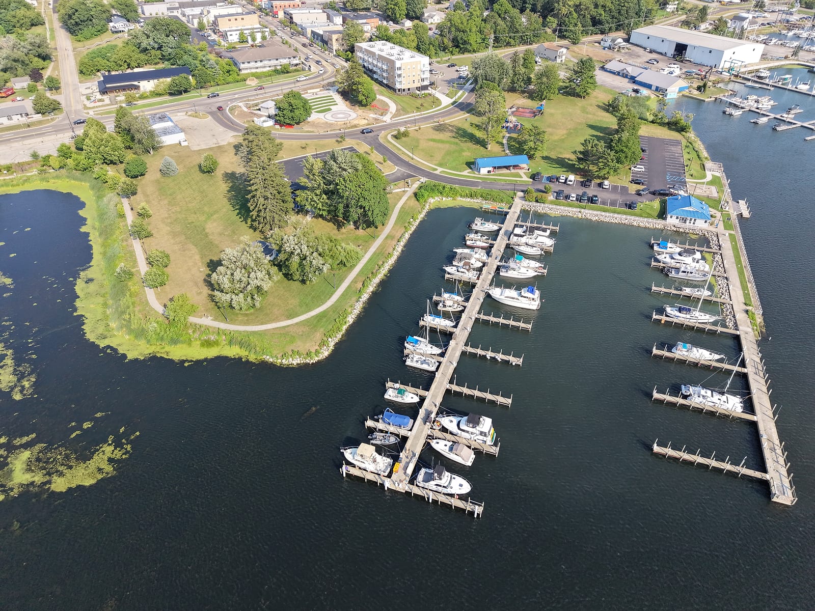 Aerial view of Goodrich Park and the White Lake Municipal Marina in Whitehall, with park paths, the pavilion, boat slips, and downtown at the top of the hill
