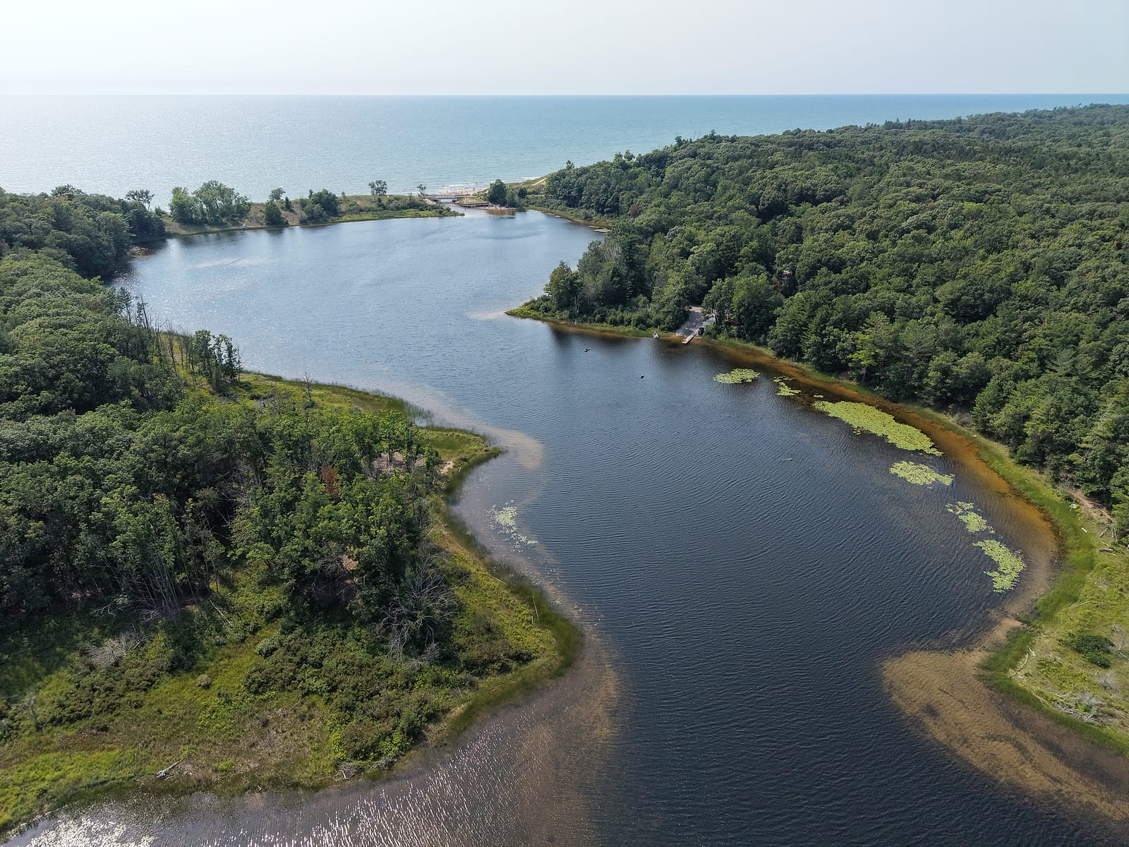 Aerial view of the west end of Duck Lake in Fruitland Township, with the lagoon, the state park dock, the Scenic Drive bridge, and Lake Michigan beyond