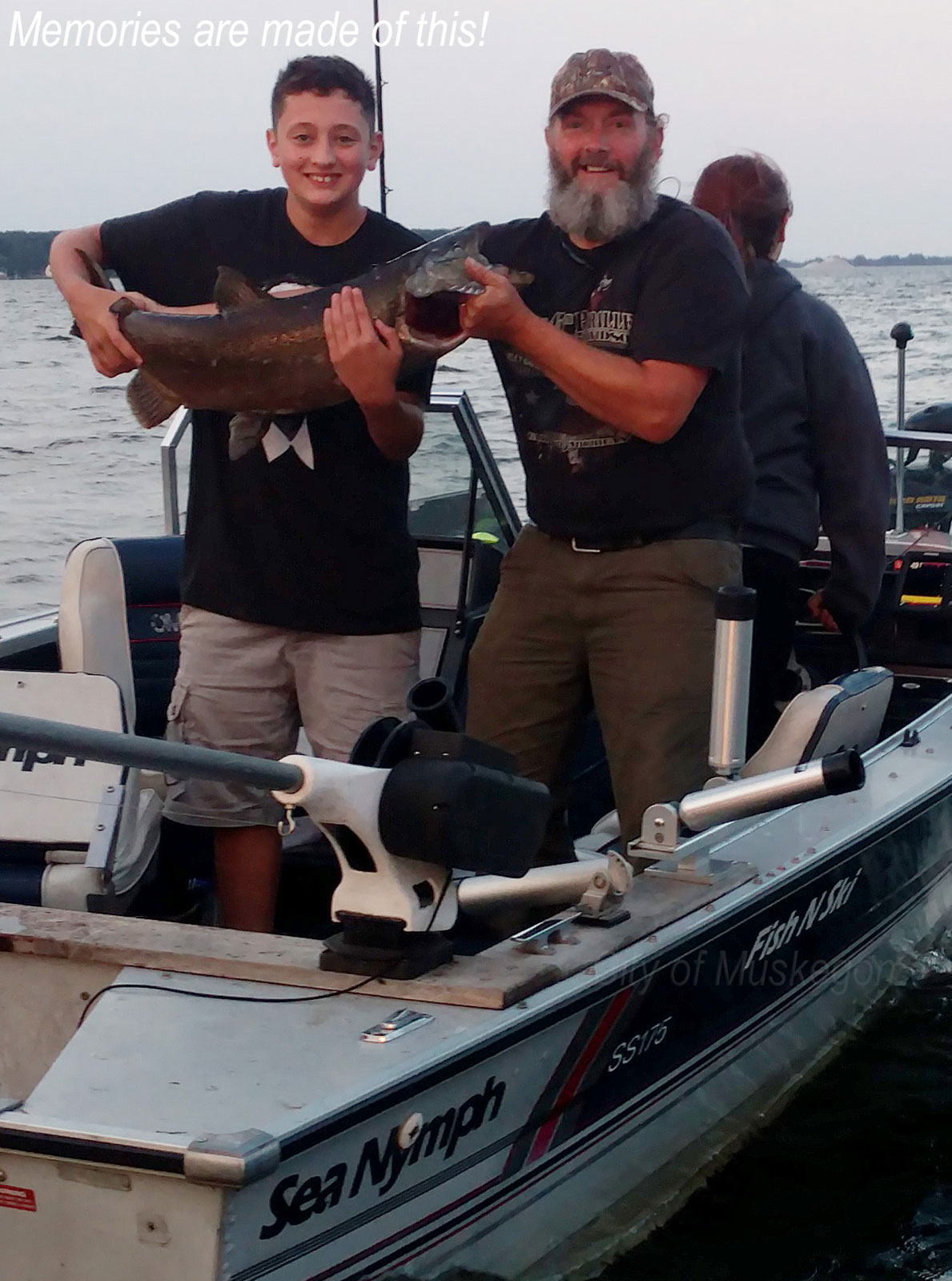 Father and son holding a salmon caught while fishing on Muskegon Lake