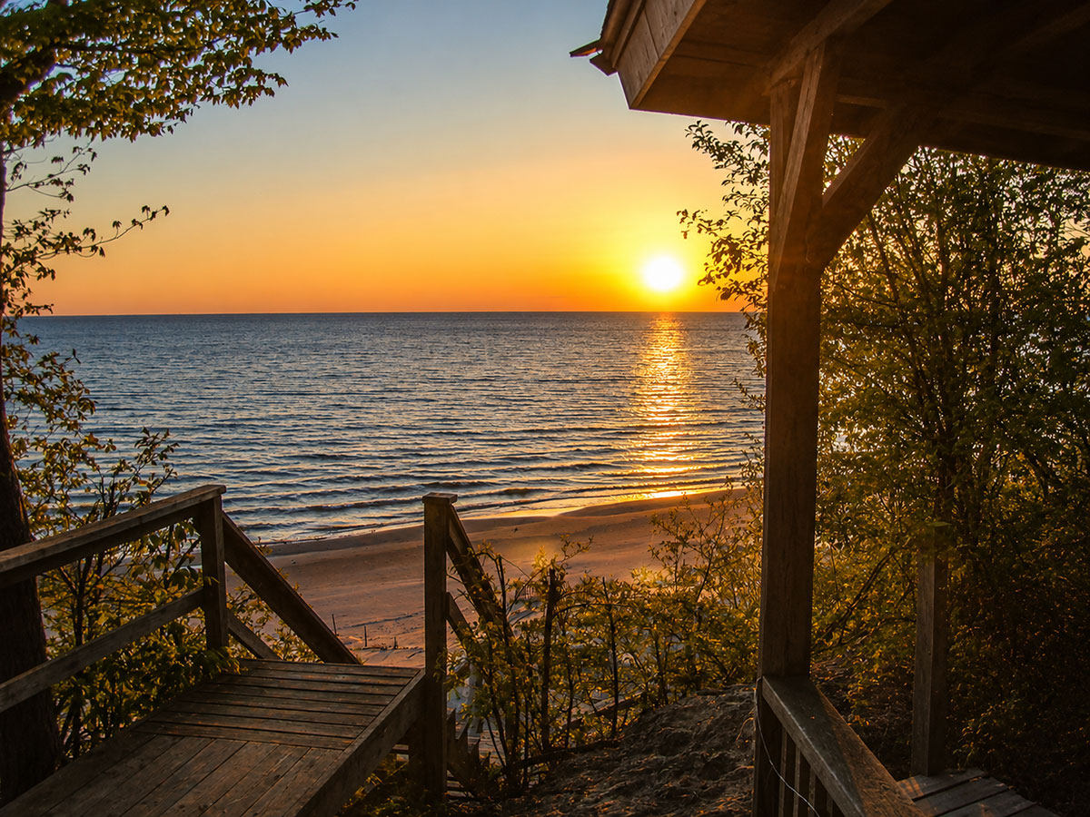 Deeded Lake Michigan beach access stairs leading through dunes to a shared beach at sunset