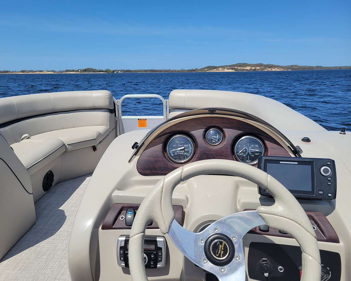 Pontoon boat on a calm day facing the Muskegon sand dunes on Lake Michigan