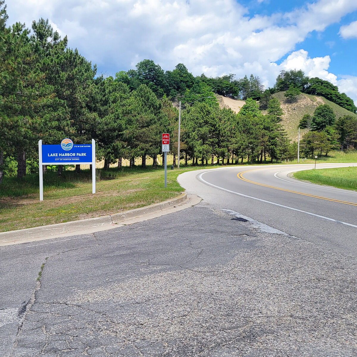 Lake Harbor Park entrance sign in Norton Shores with a Lake Michigan dune behind it