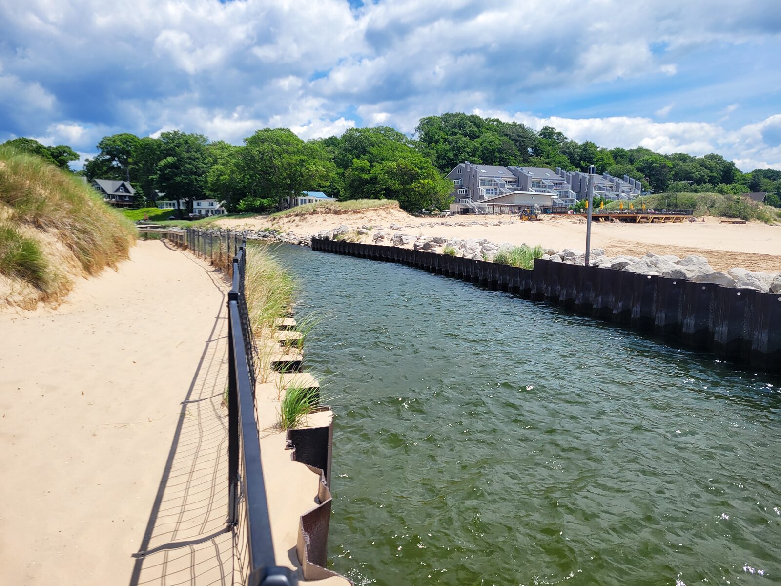 The steel-walled lower Mona Lake channel and dune-backed beach at Lake Harbor Park, near the Lake Michigan end