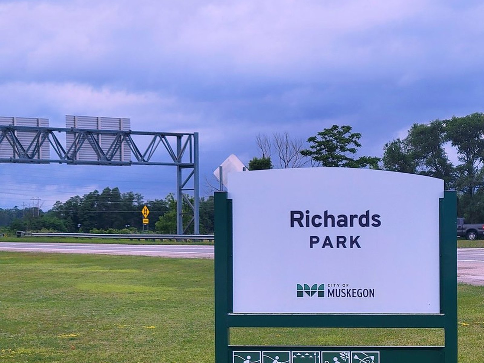 City of Muskegon entrance sign for Richards Park along the causeway, with icons for activities like hiking, biking, fishing, and paddling.