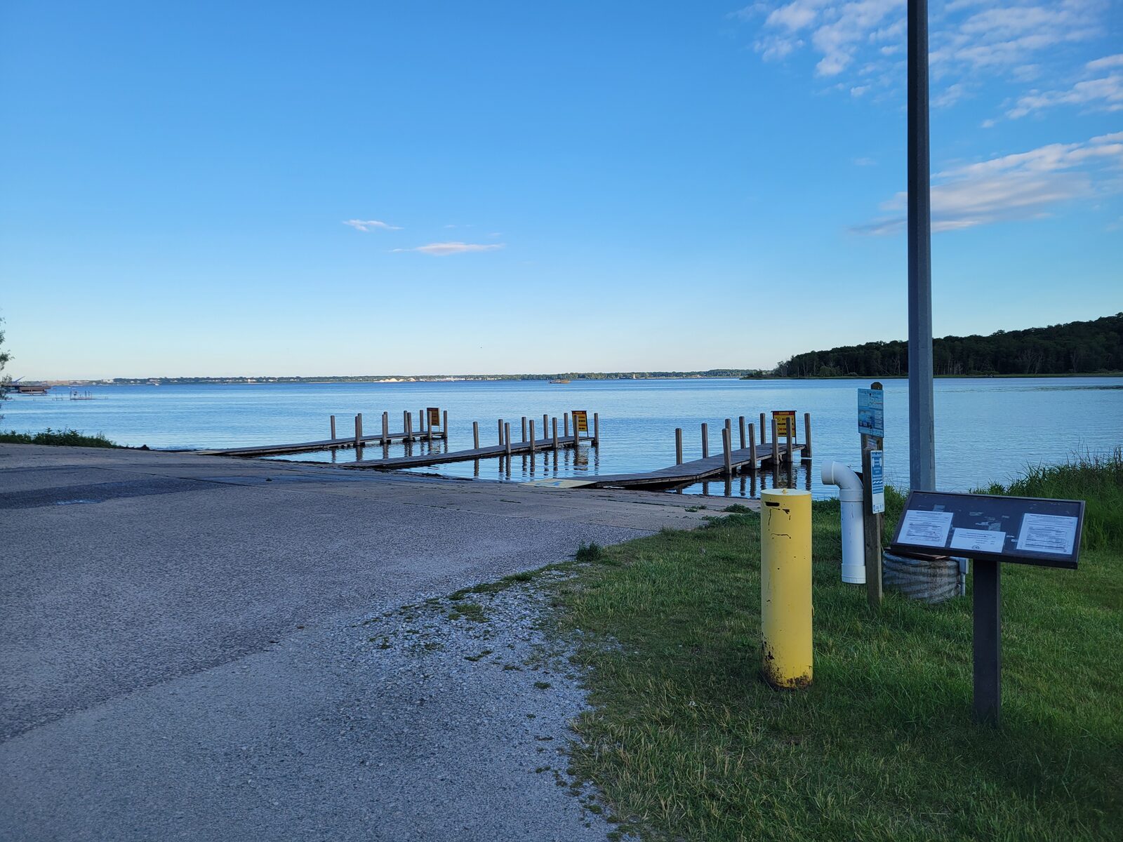 The Snug Harbor boat launch ramp and floating docks opening onto Muskegon Lake from the Muskegon State Park launch near the Lake Michigan channel on a clear June evening.