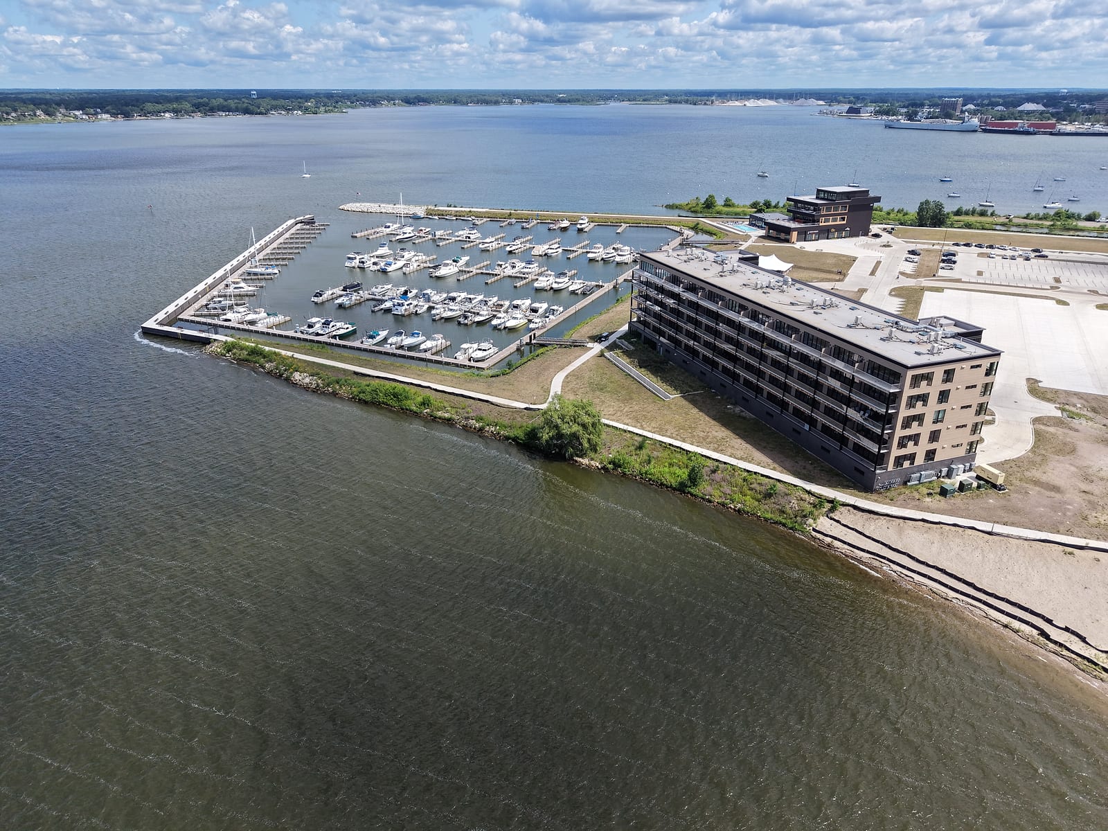 Adelaide Pointe from the air: the new marina's slips, the condo building, and the building home to Muskegon Brewing Company on Muskegon Lake, with open graded ground around the development