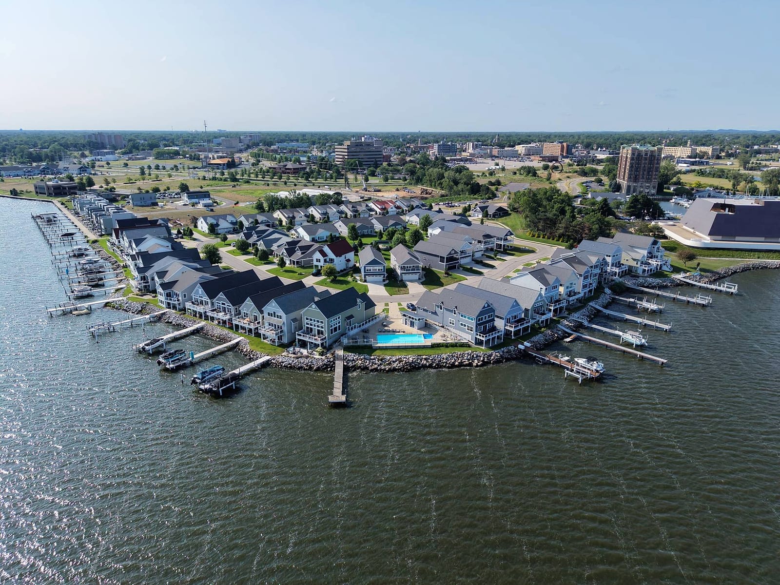 Terrace Point Landing from the air: homes and private docks on Muskegon Lake's downtown shore, with the shared pool at the water's edge