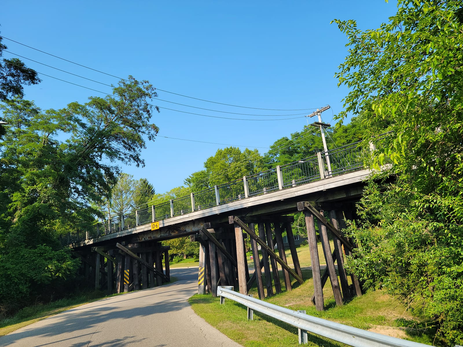 The 1930 wooden rail trestle over South Lake Street in Whitehall with the bike trail on top and the road narrowed to one lane beneath a posted 10 foot 6 inch clearance