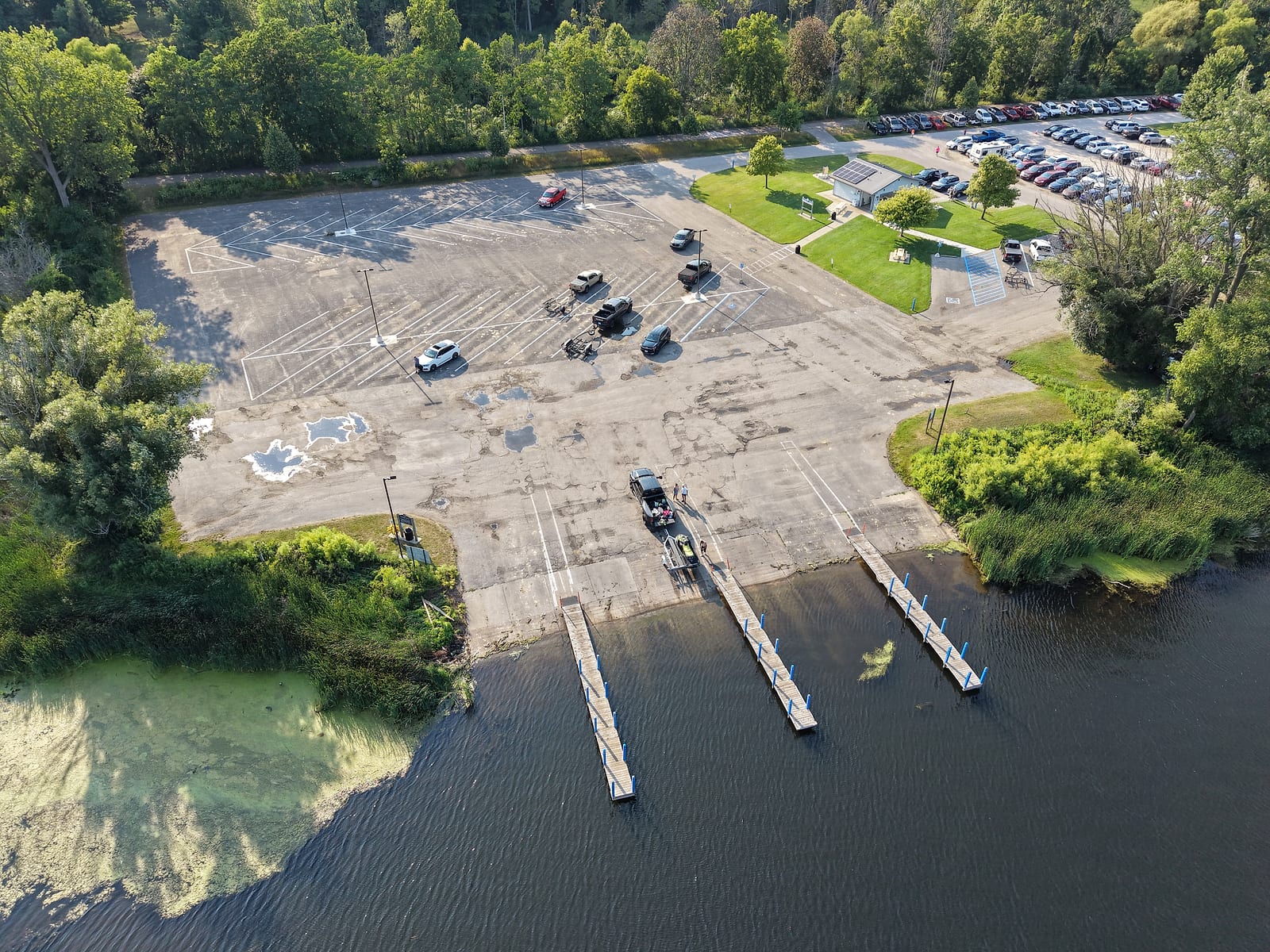Aerial view of the Montague Municipal Boat Launch on upper White Lake with three docks, launch lanes, and a large trailer parking lot