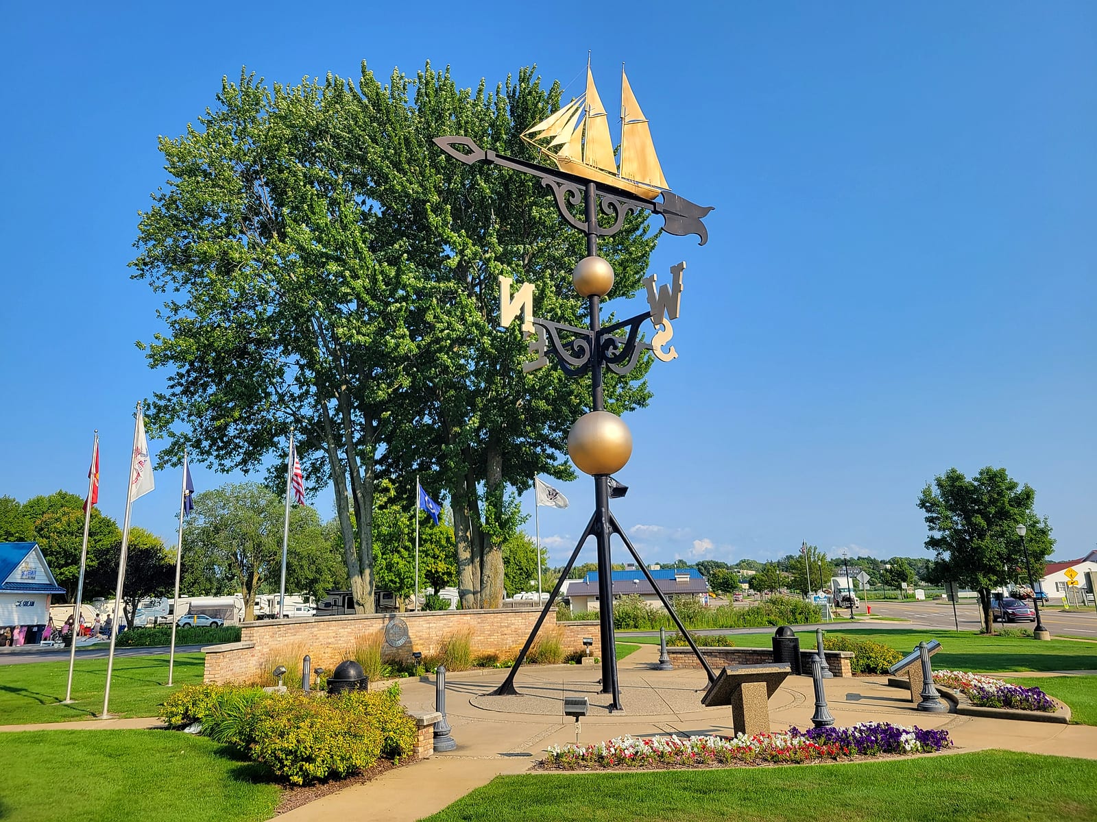 The Montague weathervane with the golden Ella Ellenwood schooner on top against a blue sky, memorial flags and plaza around its base