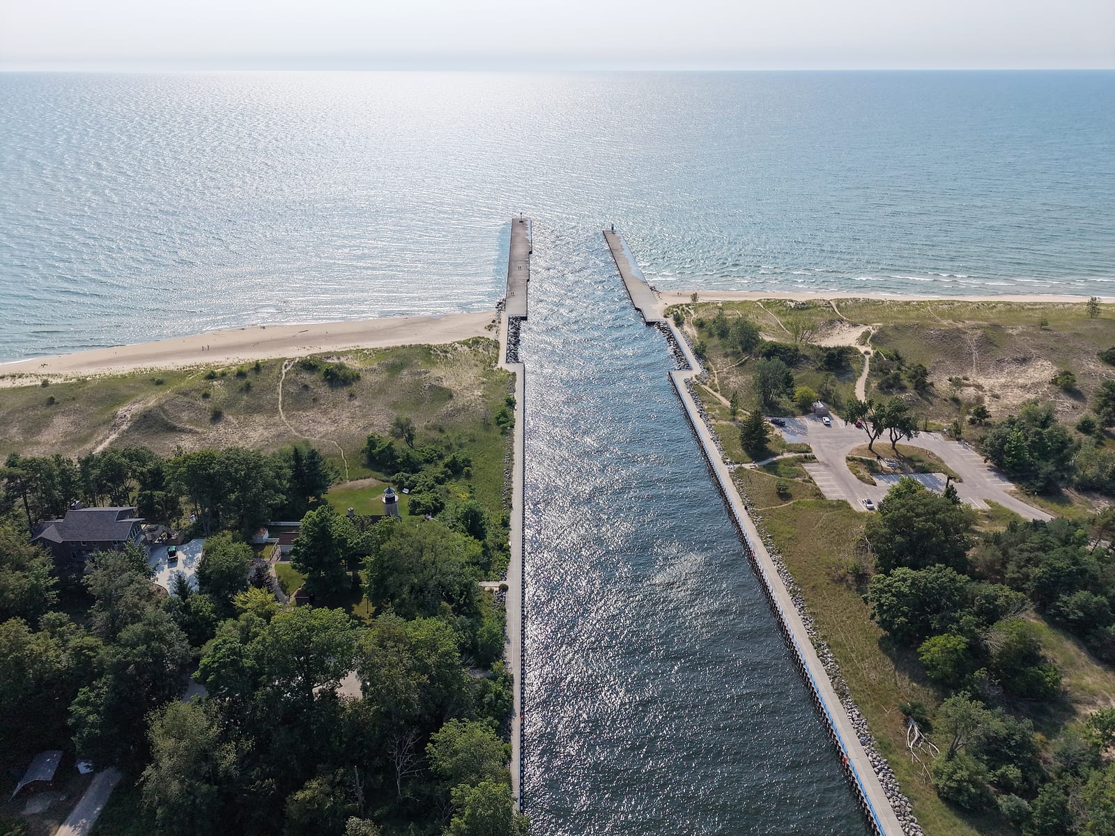 Aerial view down the White Lake channel between its two piers out to open Lake Michigan, with dune beach on both sides