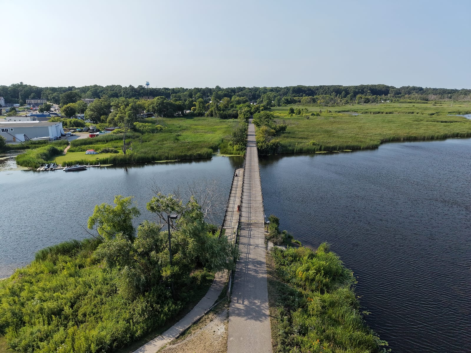 The White Lake Pathway rail-trail bridge crossing the White River toward Montague through marsh grass, seen from above the trail