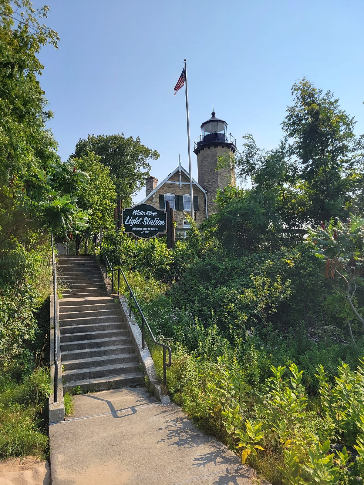 White River Light Station limestone tower and keeper's house behind the museum sign and steps beside the White Lake channel